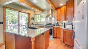 A spacious kitchen with granite countertops, wooden cabinets, a stainless steel range, and a large island with a sink. - Quiet Presque Isle Home w/ Grill: Families Welcome (Presque Isle)