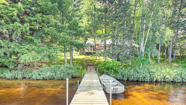 A wooden dock leading to a house surrounded by dense forest. - Quiet Presque Isle Home w/ Grill: Families Welcome (Presque Isle)