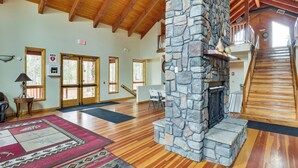 A spacious lobby with a stone fireplace, wooden floors, and a staircase leading to an upper level. - Hike & Fish: Cozy Cabin w/ Patio in Show Low! (Show Low)