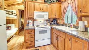A compact kitchen with wooden cabinets, a microwave, and a stove. - Hike & Fish: Cozy Cabin w/ Patio in Show Low! (Show Low)
