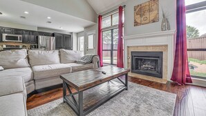 Ein Wohnzimmer mit Sofa, Couchtisch, Kamin und Küchenzeile.