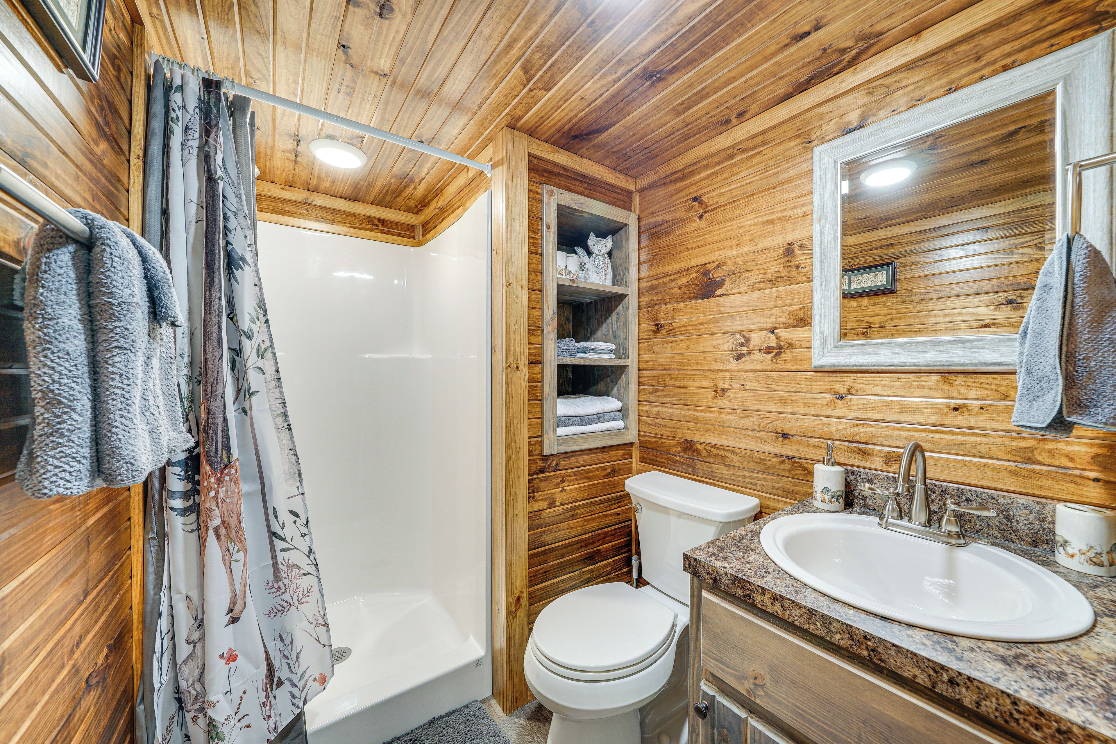 A wooden-paneled bathroom with a shower, toilet, and sink.