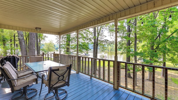 A covered deck with a table and chairs, overlooking a lake and trees. - Waterfront Wheeler Lake Home w/ Furnished Deck (Athens)