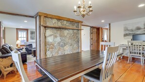 A dining area with a stone wall, wooden table, and white chairs. - Walk to Memorial Park: Pet-friendly Bethlehem Home (Bethlehem)