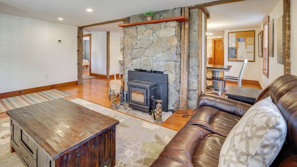 A living room with a stone fireplace, a leather sofa, and a wooden coffee table. - Walk to Memorial Park: Pet-friendly Bethlehem Home (Bethlehem)