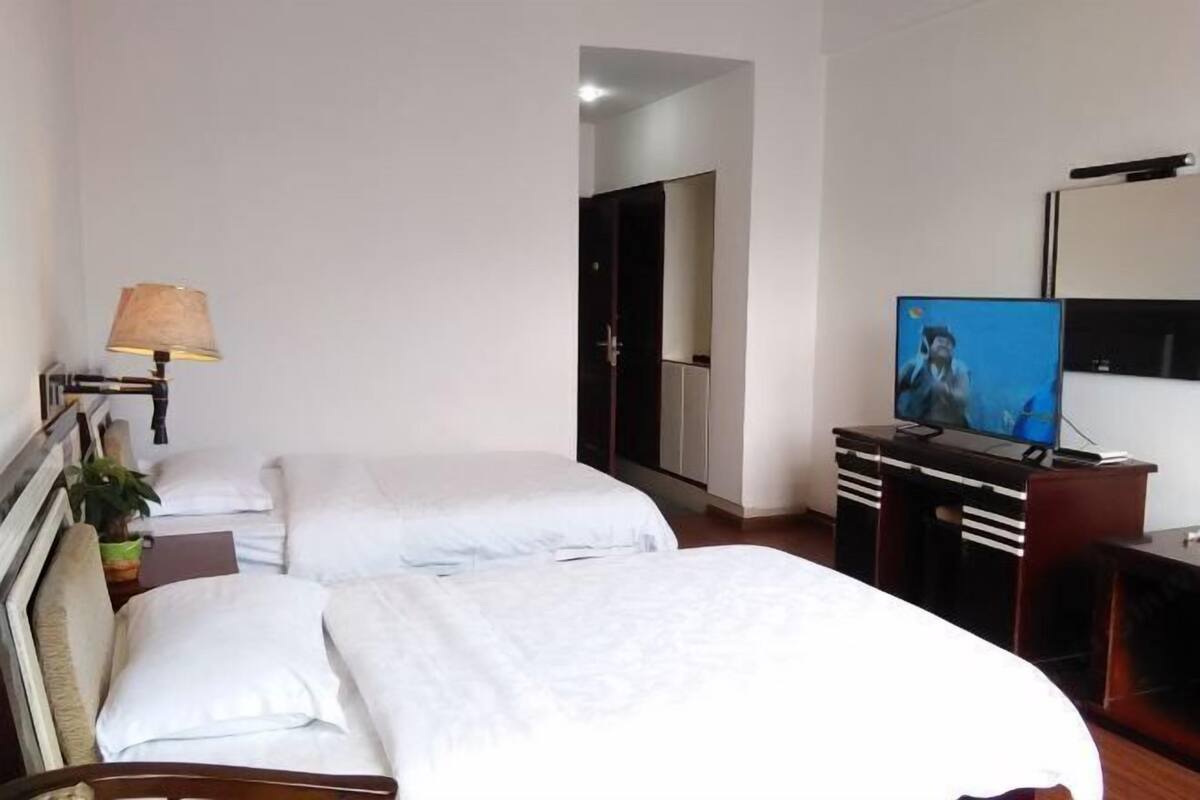 Une chambre d’hôtel avec deux lits, une télévision, un bureau et une lampe.