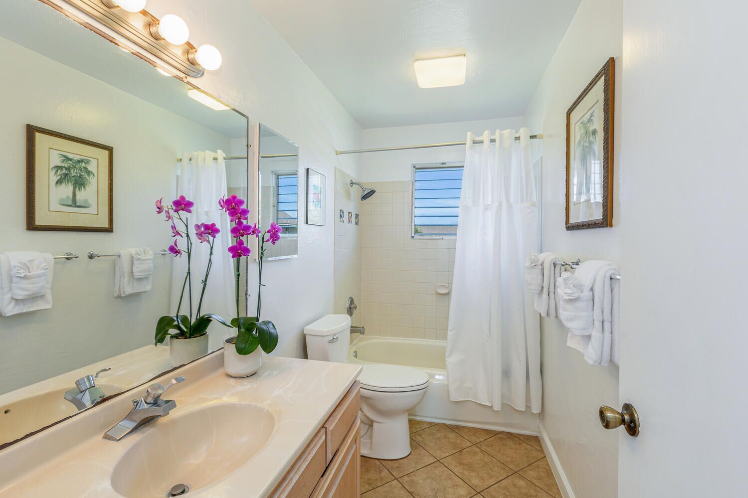 A bathroom with a sink, toilet, and bathtub. There are towels hanging on the wall and a shower curtain.