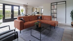 Ein modernes Wohnzimmer mit einer Eckcouch, einem Couchtisch sowie Blick auf die Küche und den Balkon.