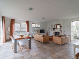Un amplio espacio habitable con una mesa de comedor, sillas, un sofá y una chimenea.