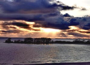 A body of water with a distant landmass and a cloudy sky.