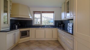 Eine moderne Küche mit beigen Schränken, einer schwarzen Arbeitsplatte und einem Fenster, das für natürliches Licht sorgt.