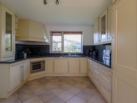 A modern kitchen with beige cabinetry, a black countertop, and a window providing natural light.