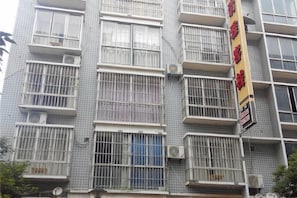 Un edificio de varios pisos con ventanas protegidas por barrotes y unidades de aire acondicionado.
