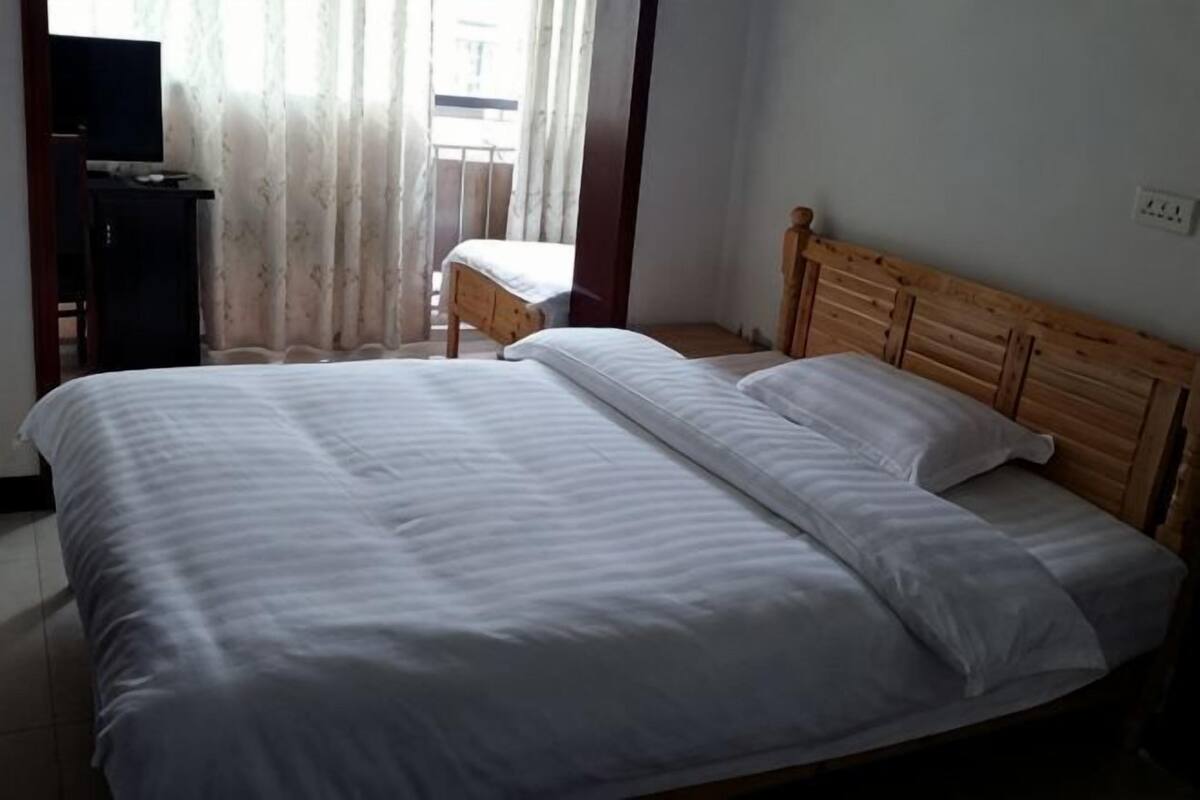 Un lit avec du linge de lit blanc, une tête de lit en bois et une petite table de chevet.