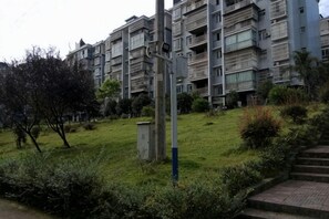 Un edificio residencial con varios balcones, una zona verde y un cuadro de empalmes.