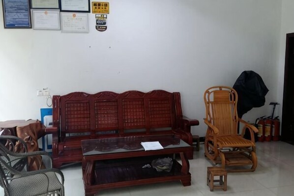 A room with a wooden sofa, a wooden chair, a small table, and a fire extinguisher. - Qingya Inn on the West Grand Canyon Hot Spring (Shuifu)