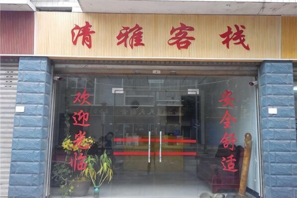 A storefront with a sign that reads '清雅客栈' and decorative red Chinese characters on the glass door. - Qingya Inn on the West Grand Canyon Hot Spring (Shuifu)