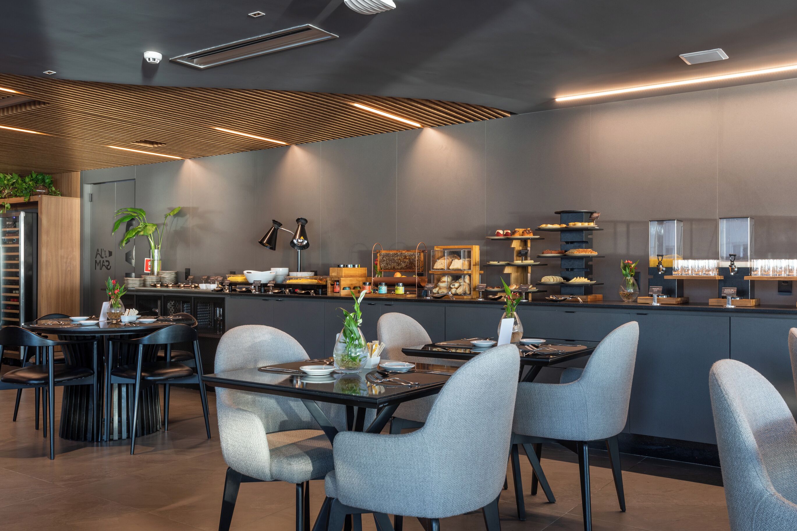 A modern restaurant with a central dining area, a bar, and a kitchen visible in the background.