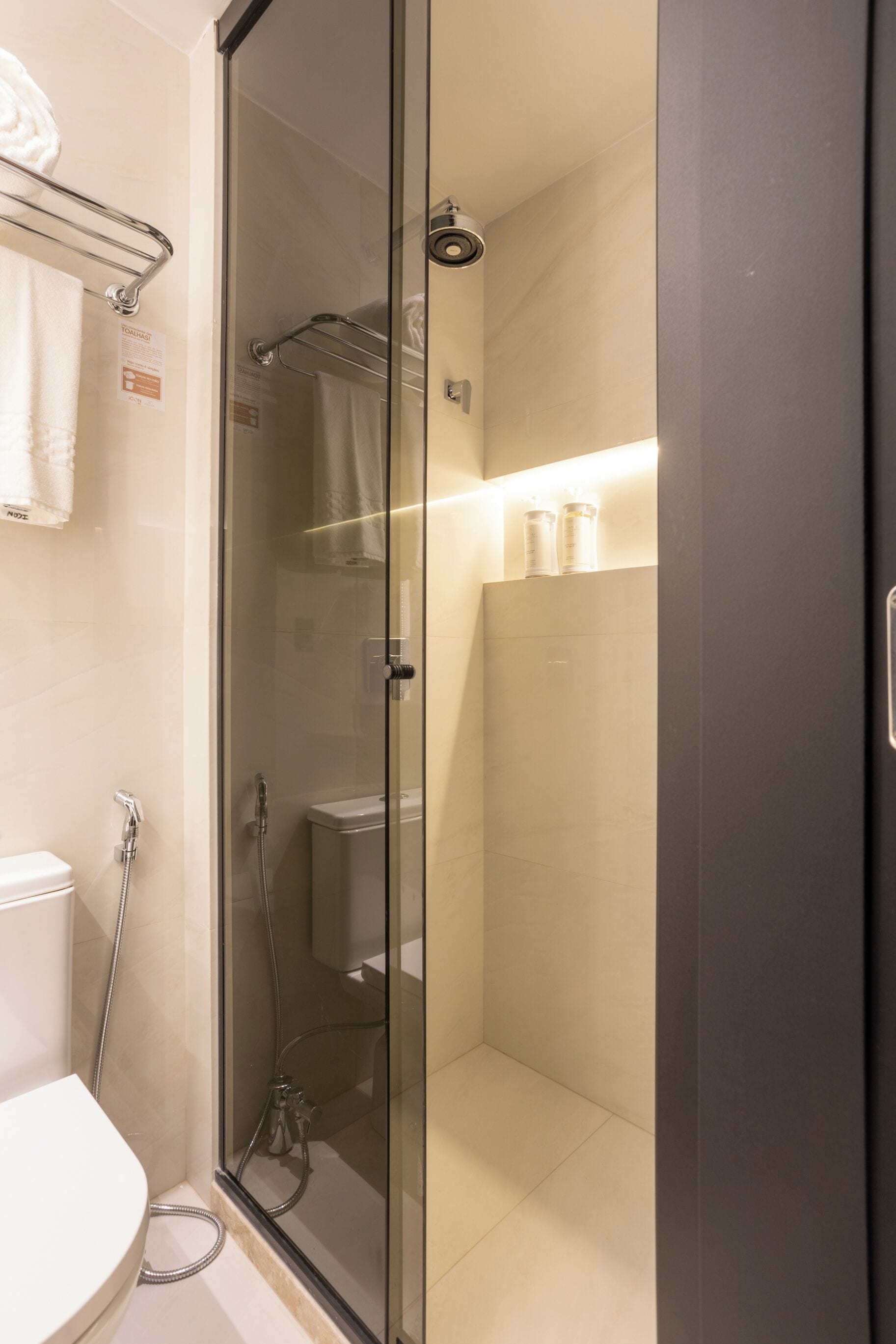 A modern bathroom with a glass-enclosed shower, a toilet, and a sink.