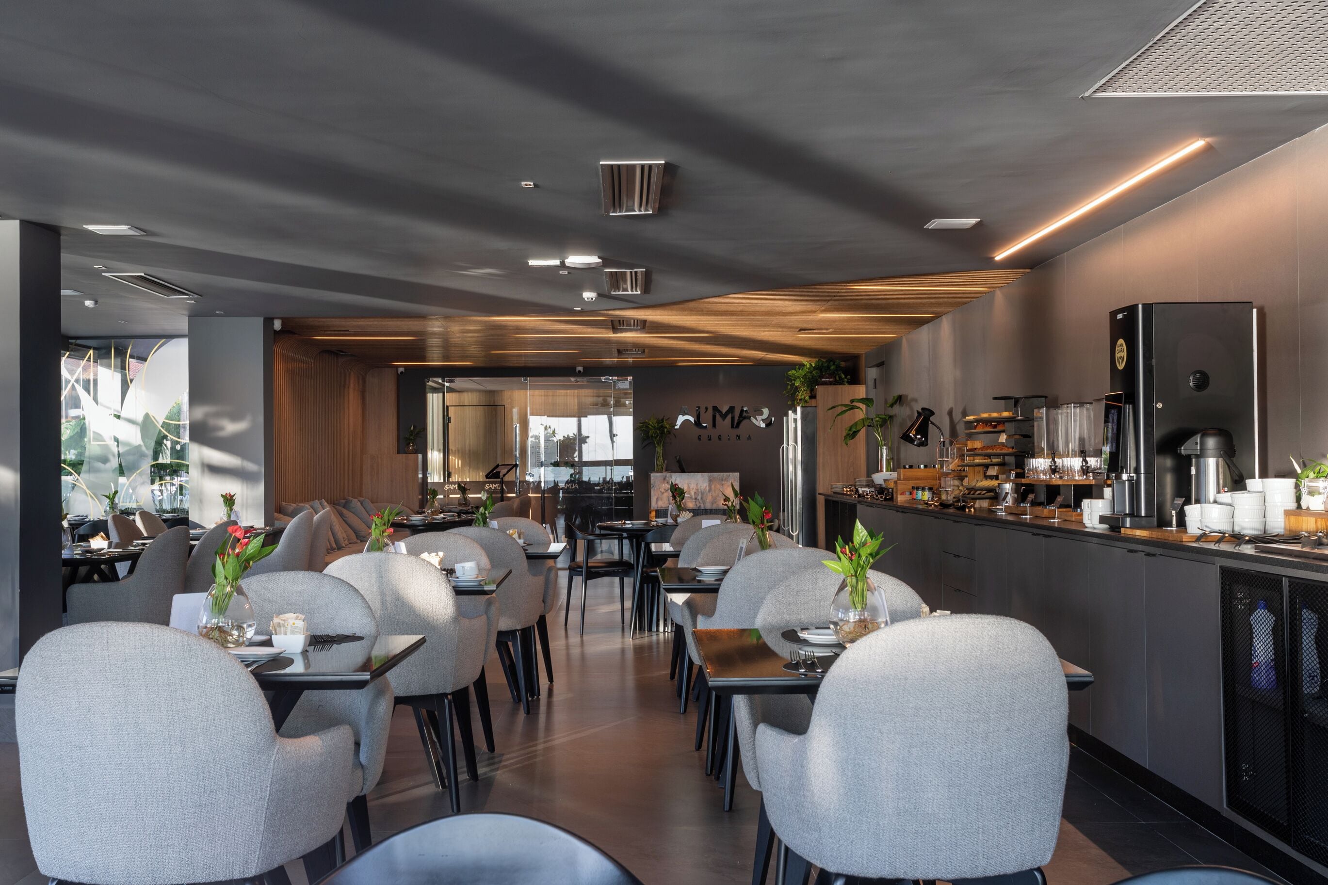 Ein modernes Restaurant mit Barbereich, Sitzgelegenheiten für 20 Gäste und einer im Hintergrund sichtbaren Küche.