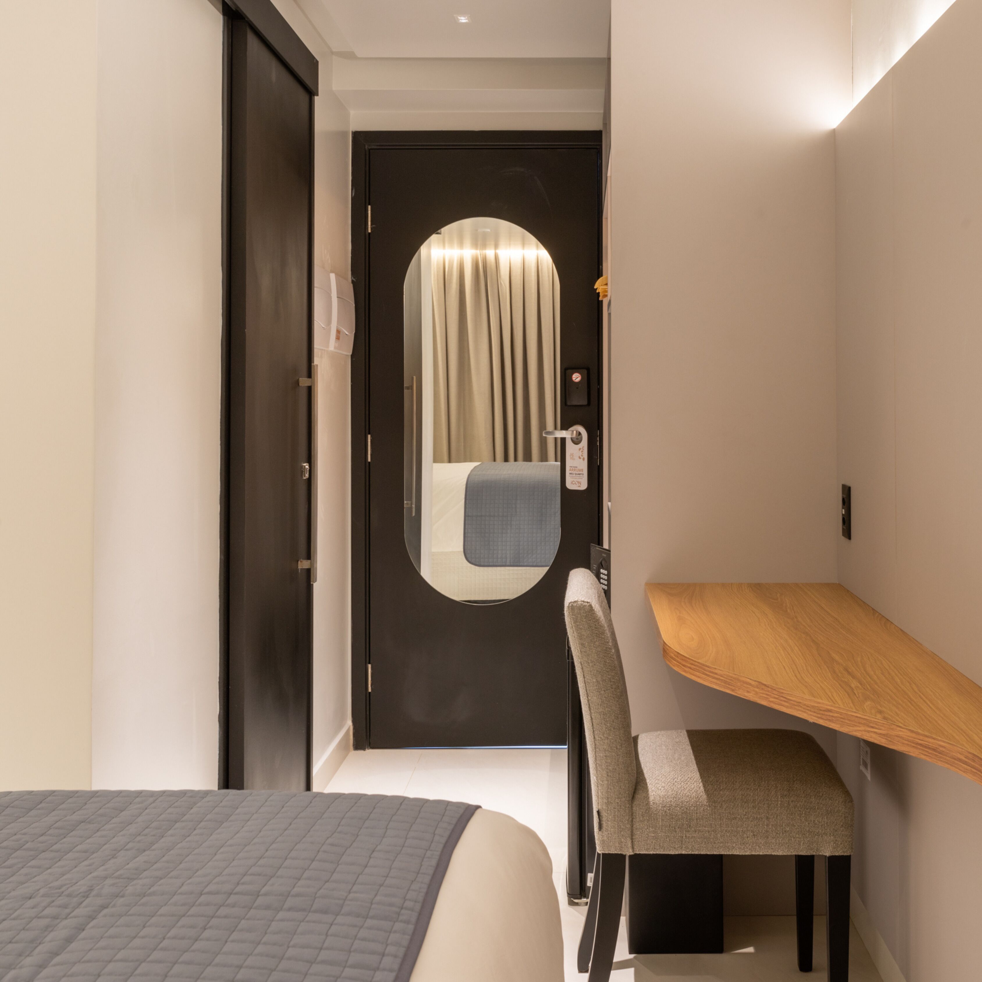 A hotel room with a bed, a desk, and a chair.