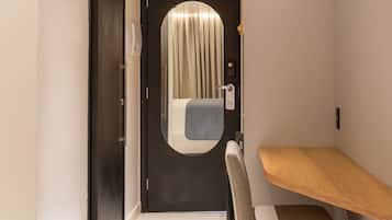 A hotel room with a bed, a desk, and a chair.