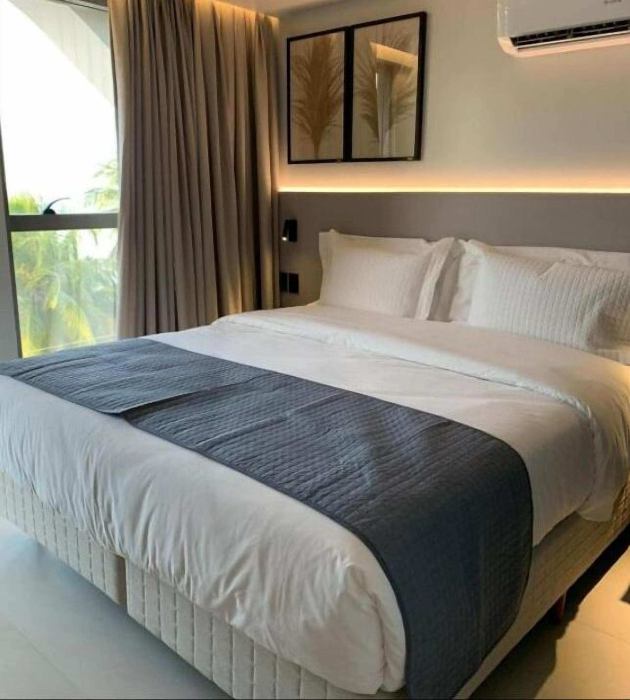 Habitación de hotel con una cama grande, vista a zonas verdes y un diseño moderno.