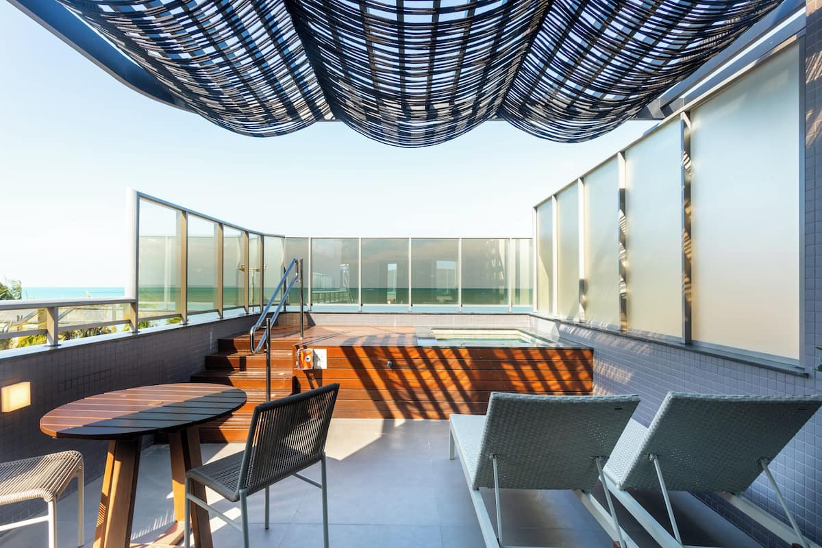 A rooftop terrace with a glass balustrade, a wooden deck, and seating areas.