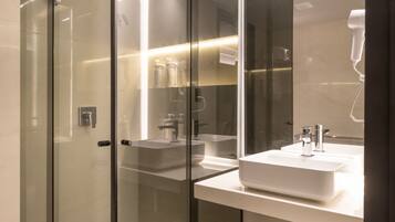 A modern bathroom with a glass shower enclosure, a large mirror, and a white sink.