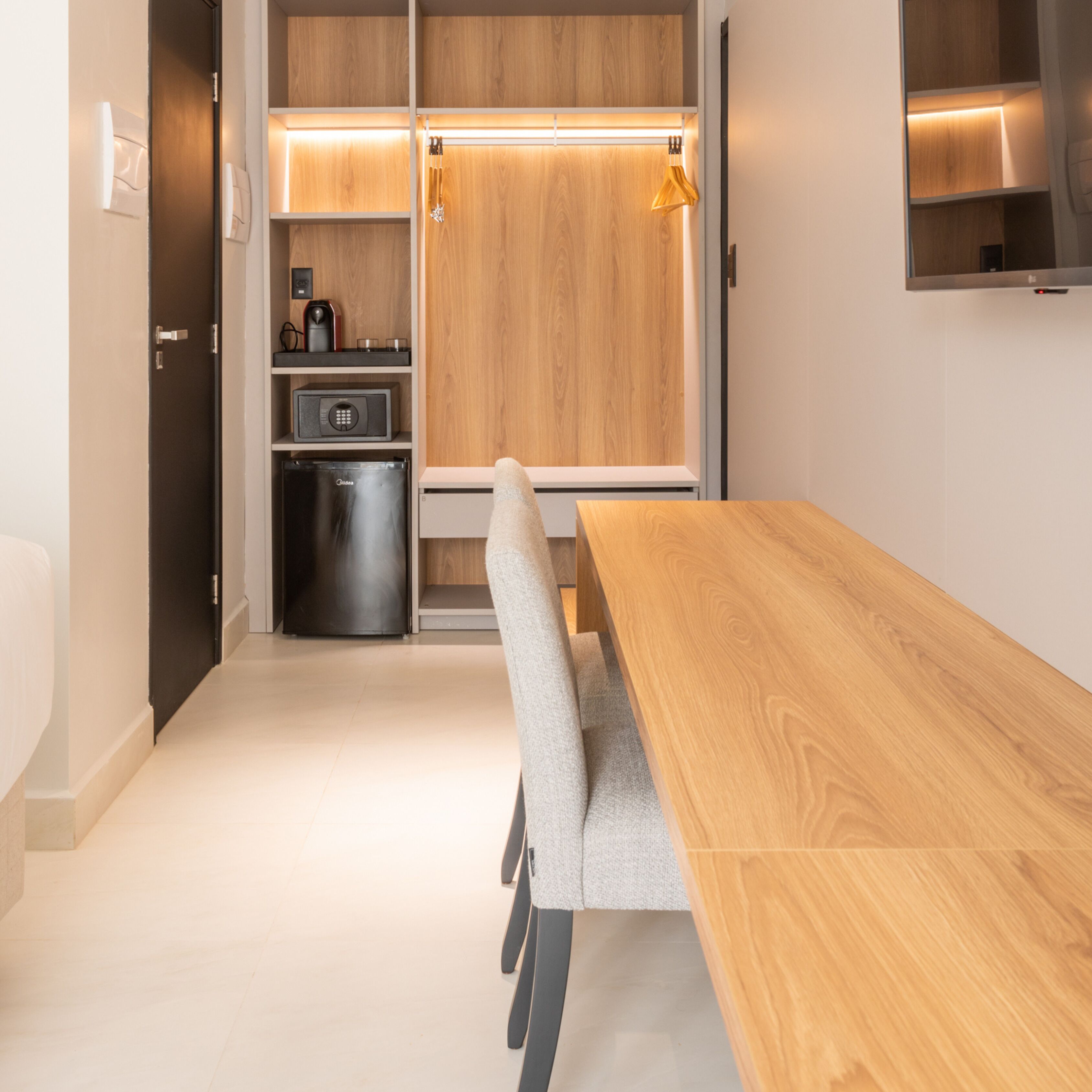 Una cocina moderna con una mesa y sillas de madera, electrodomésticos integrados y un televisor fijado a la pared.