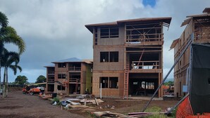 Un edificio de varios pisos en construcción, con estructura de madera a la vista y el interior sin terminar.