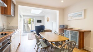 A modern kitchen with a wooden dining table, grey chairs, and a built-in microwave. - Host Stay Prince Albert (Margate)