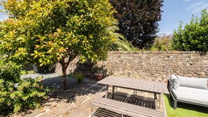 A patio area with a stone table and bench, a white sofa, and a stone wall. - Host Stay Prince Albert (Margate)