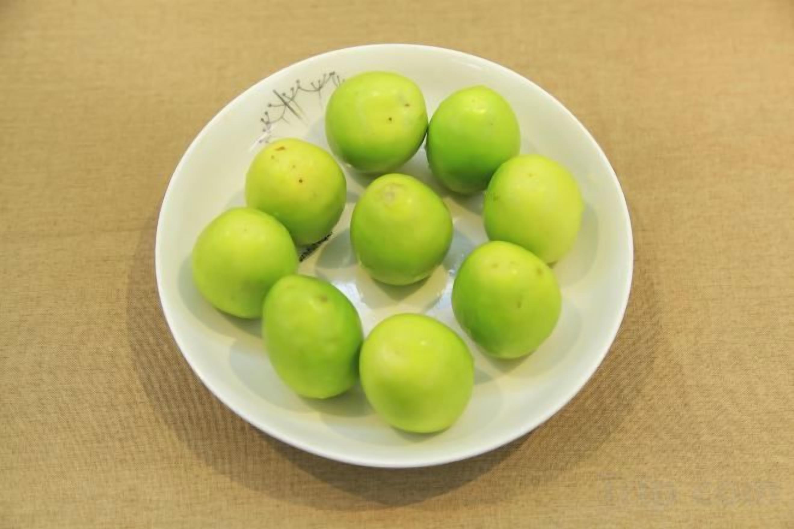 A white plate with green apples on a textured surface.