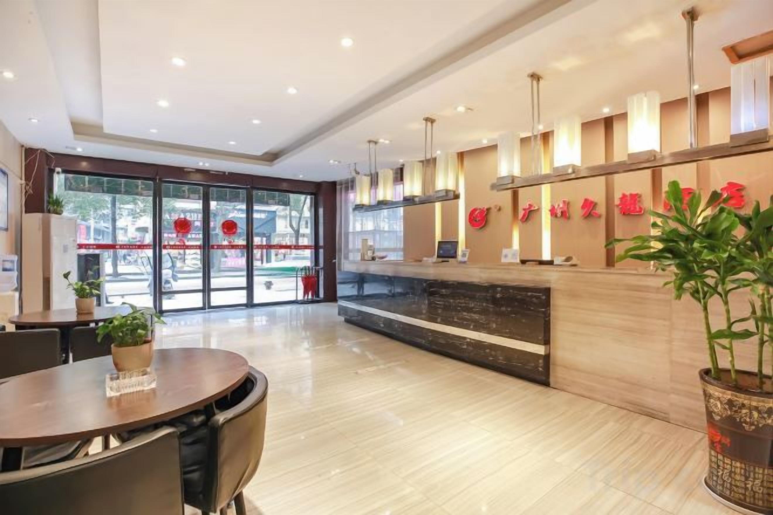 A hotel lobby with a reception desk, seating area, and large windows.