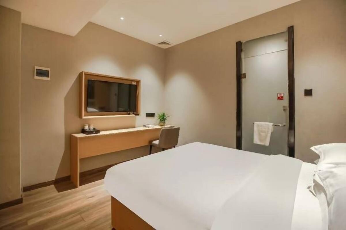 Een hotelkamer met een bed, een bureau met een computer, een spiegel en een deur.
