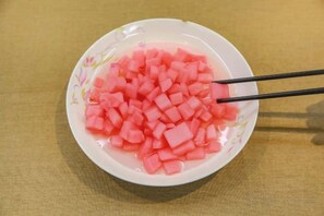 A bowl of diced pink food with chopsticks on a table. - Guangzhou Jiulong Hotel (Sansui Fuzheng West Road Branch) (Sansui)