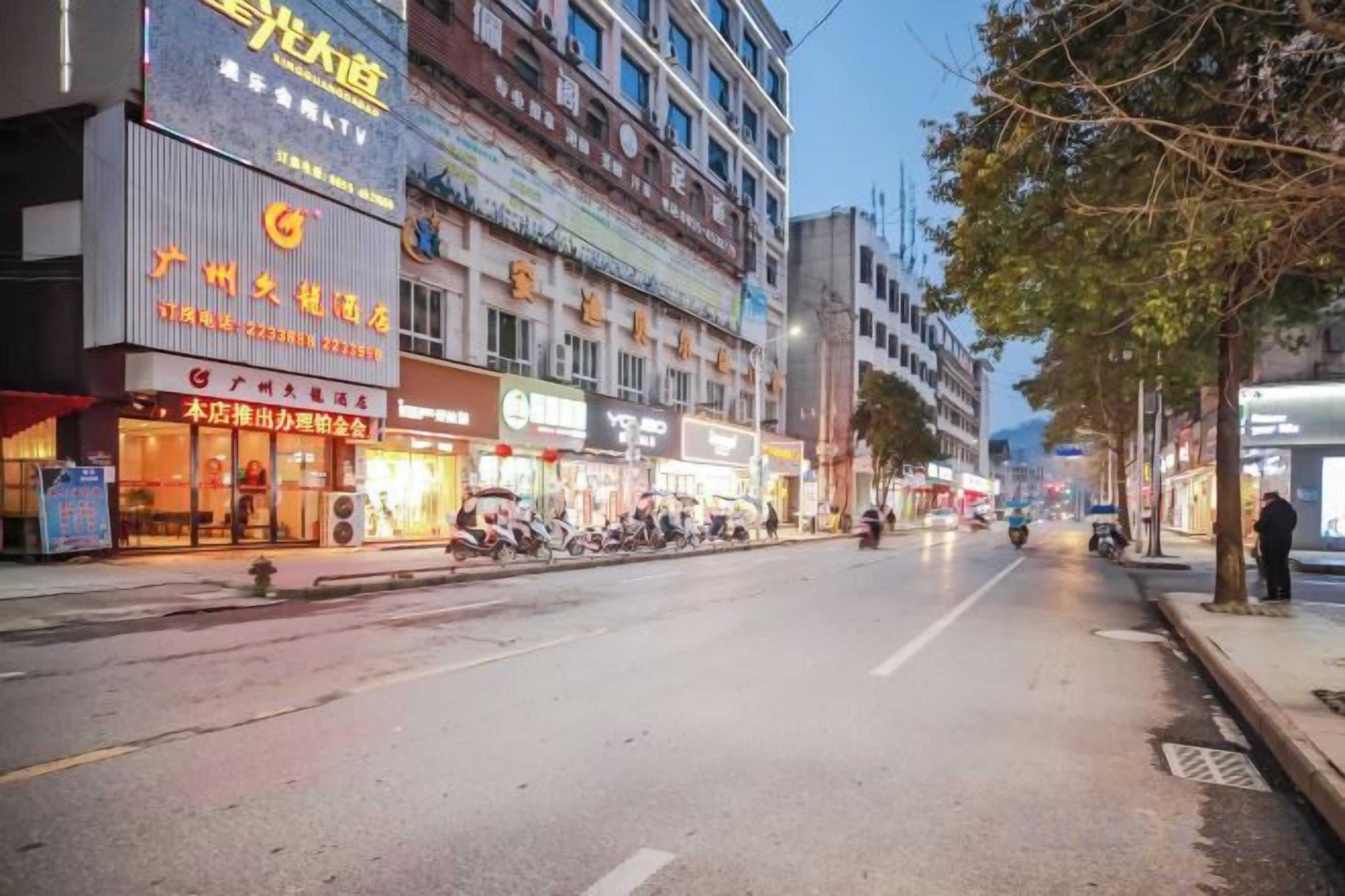 A street with commercial buildings, some with signage in a foreign language, and a few parked motorcycles.