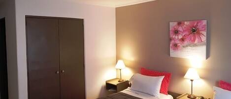 Quarto de hotel com cama, duas mesas de cabeceira com luminárias, um quadro na parede e um guarda-roupa.