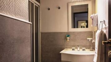 A bathroom with a sink, mirror, towel rack, and a bidet.