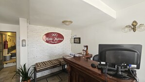 Egy recepciós pult, rajta egy számítógéppel, egy pad és egy „Hostal Malvinas” felirattal ellátott tábla.