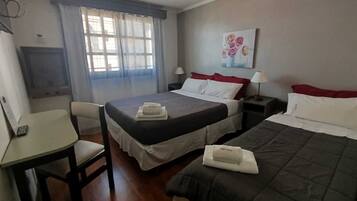 Ein Hotelzimmer mit zwei Betten, einem Schreibtisch und einem Fernseher.