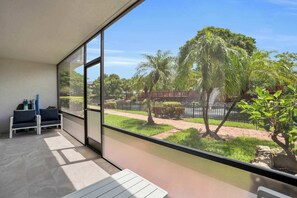 A balcony with a view of a landscaped garden, including palm trees and a pathway.