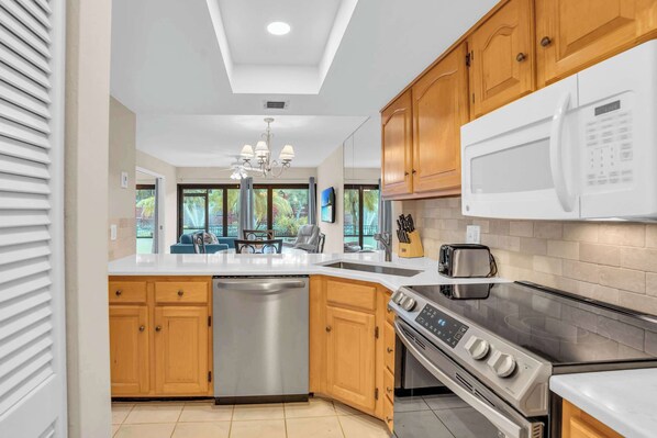 A modern kitchen with wooden cabinets, a stainless steel dishwasher, a built-in oven, and a microwave.