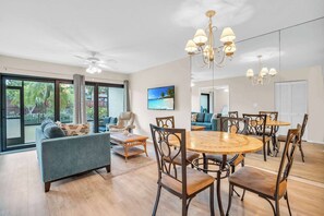 A spacious living area with a large dining table, comfortable seating, and a view of the outdoors.