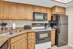 A kitchen with wooden cabinets, a stainless steel refrigerator, a microwave, a stove, and a sink. - G-143 - First Floor With Lake Views -Sleeps 6 (Naples)