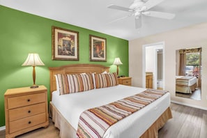 A hotel room with a large bed, two bedside tables, a ceiling fan, and two framed pictures on the wall. - G-143 - First Floor With Lake Views -Sleeps 6 (Naples)