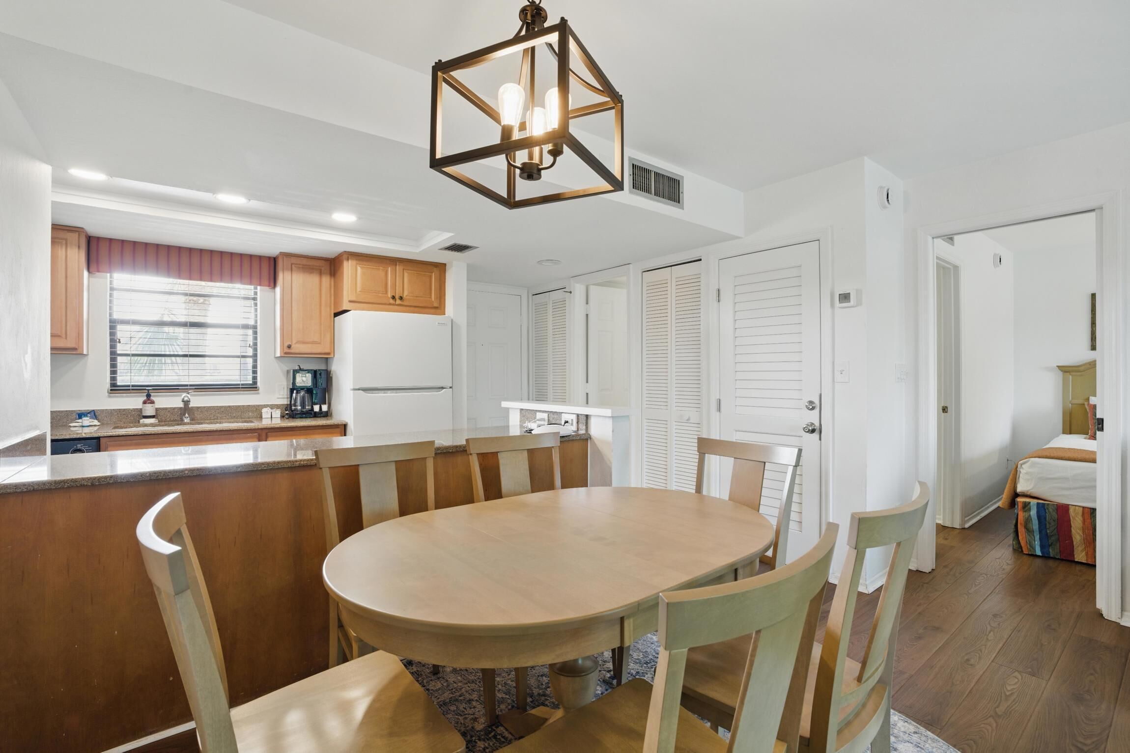 Una cocina moderna con una isla central, armarios de madera y una lámpara colgante.
