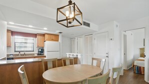 A modern kitchen with a central island, wooden cabinets, and a hanging light fixture.
