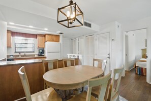 A modern kitchen with a central island, wooden cabinets, and a hanging light fixture. - E-233 - Deluxe Condo with Lake Views & Sleeps 6 (Naples)